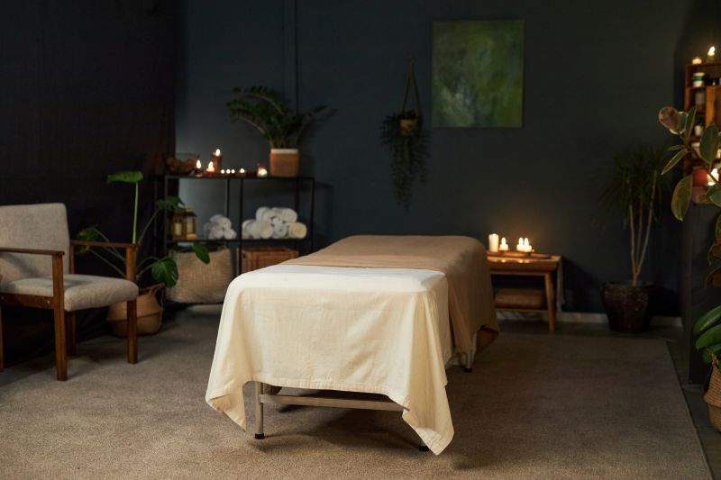 Peaceful massage therapy room setup with soft linens, warm light, and plants creating a safe space for trauma-aware bodywork.