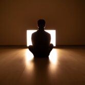 Person sitting in meditative pose with warm light, reflecting calm and safety during somatic trauma therapy.